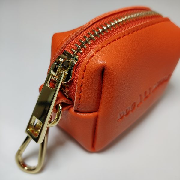 Dog A La Mode Le Classique orange vegan dog poop bag holder close up with a durable brass hook to easily attach to leashes, harnesses and collars