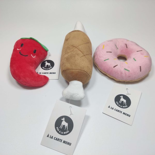 Dog A La Mode's new Dog A La Carte lunch meal dog toy set of three plush squeaky dog toys. This cute dog toy set includes the suffed pepper dog toy, the meat on bone dog toy and the sprinkled doughnuts dog toy with Dog A La Mode hang tags on each dog toy