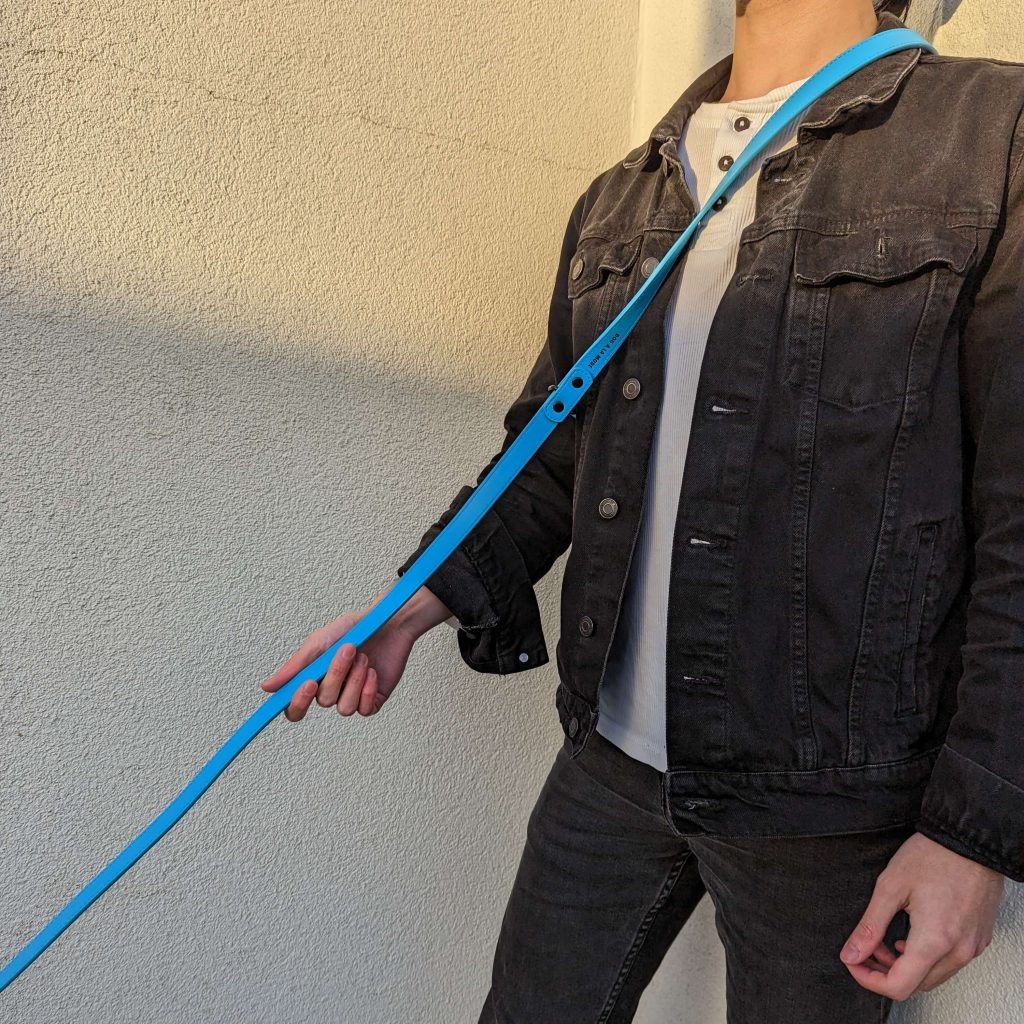 Man wearing and holding the new Dog A La Mode hands free and double ended blue vegan dog leather across the shoulder